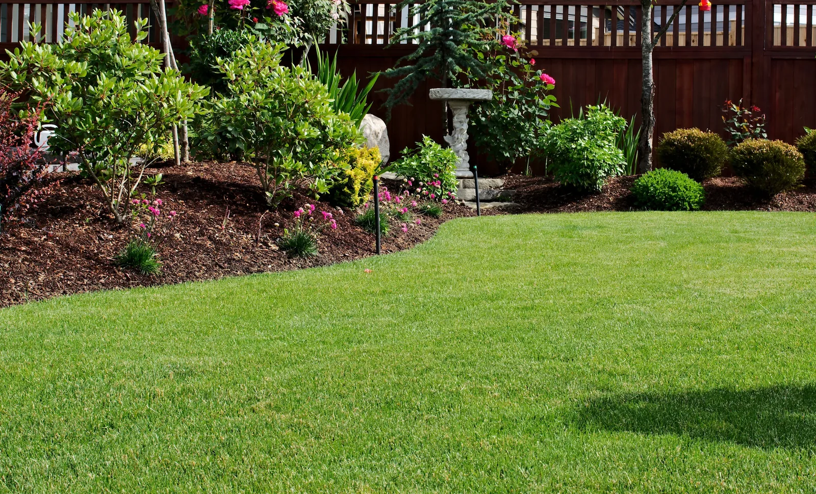 Freshly mulched planting beds around a maintained backyard